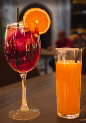 View of glass of sangria with slice of orange and glass of orange juice on table
