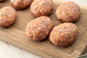 raw homemade meatballs on a massive board made of natural wood