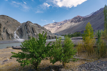 beautiful landscape with green trees and blue sky, mountains in the background at Ladakh, in the Indian Himalayas.