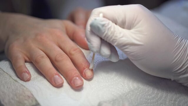 A beautician rubs oil into the cuticles of a beauty salon client