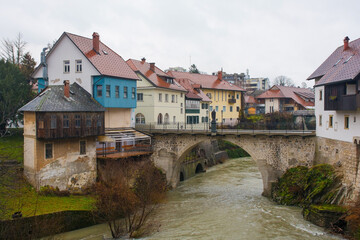 Fototapeta na wymiar A wet December day in Skofja Loka in Gorenjska, Slovenia. The Capuchin Bridge crossing the Selska Sora river as it flows through the historic centre