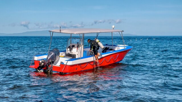 An unidentied resort boatman loads air tanks into the boat in preparation for the next group scuba dive, in the Philippines.