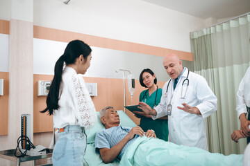 Obraz premium professional doctor standing by explain the treatment information via male elderly patient lying in bed in private hospital sickroom. The treatment program is suitable for people to socialize elderly