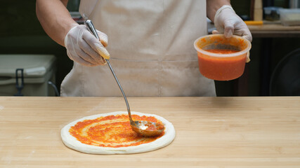 chef makes pizza with his hands putting the ingredients for the pizza on the table. The dark background.