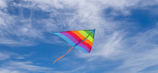 rainbow kite flying against a blue sky.