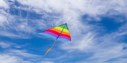rainbow kite flying against a blue sky.