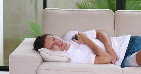 Upset man reads message on smartphone about bad news he was dumped by girlfriend. Portrait male millennial lying on couch, suffering from relationship problems. Concept of man abandoned by girlfriend