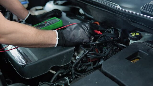 Technician uses multimeter voltmeter to check voltage level in car battery, close up. Service and Maintenance car battery
