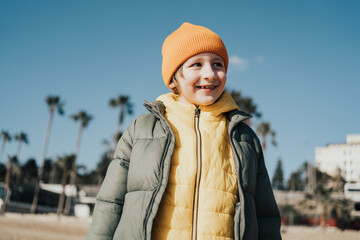 Fototapeta na wymiar Portrait of happy laughing child boy on the beach. Kid smiling outdoors on the autumn winter beach