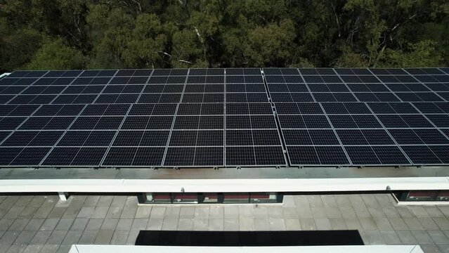 Photovoltaic cells on top of a modern building in a forest - Aerial view