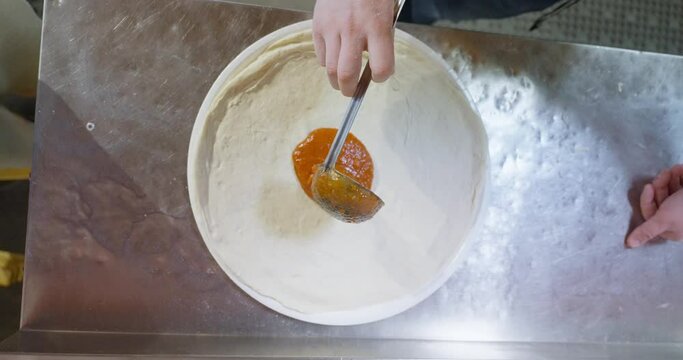 Making pizza from scratch with pizza sauce, cheese and sausage. mobile phone video, vertical video. Close up of hands making pizza.