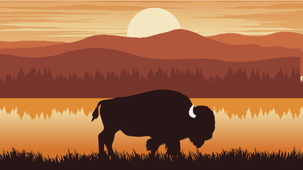 a bison is standing near a lake with mountains © DNC