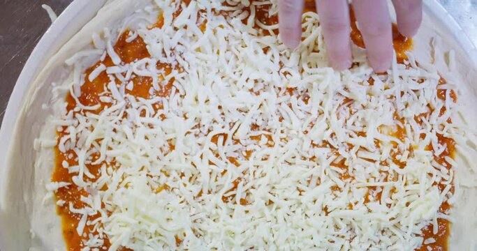Making pizza from scratch with pizza sauce, cheese and sausage. mobile phone video, vertical video. Close up of hands making pizza.