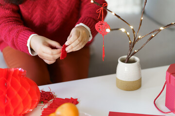 Asian Woman decorated house for Chinese New Year Celebrations. putting traditional pendant to the...