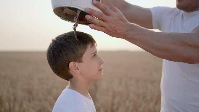 Father man son boy child teenager playing aviator cosmonaut putting helmet in sunset field, Kid big dream flying astronaut space. Concept childhood Parent dad having fun happy family together summer 