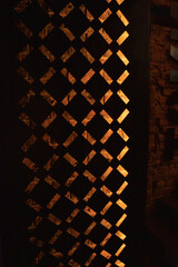 Decorative metal partition with geometric holes, illuminated brick wall. Restaurant decor.