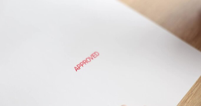 Stamp in hand on white sheet and approved text closeup