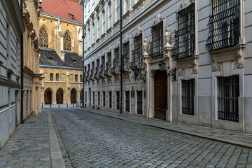 Fototapeta na wymiar Narrow cobblestone street among historic buildings in historic center of Vienna.