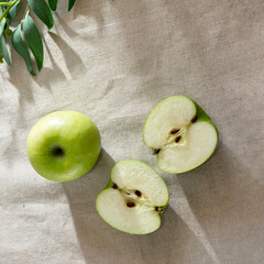 Green cut apples on table with sunlight shadows, aesthetic lifestyle composition, flat lay, copy space