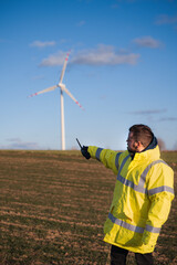 Wind turbine engineer. Male engineer maintains and controls wind turbine energy generation on the background of windmills. Concept of sustainable future.