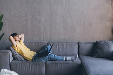 Obraz premium Young man relaxing on a sofa with his laptop