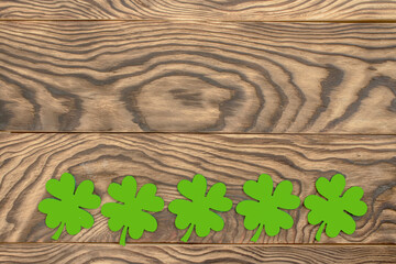Frame of four-leaf clover and light lights. Wooden background with clover leaves. St. Patrick's Day. Textured wood, blank for holiday greetings. Flat layout. copy space. - 578604351