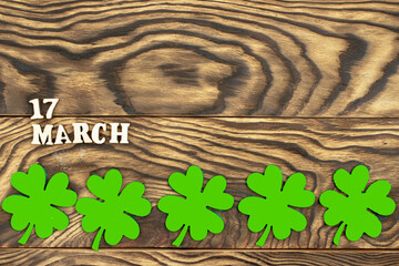 The inscription March 17 and a clover leaf on a dark wooden background. The concept of celebrating St. Patrick. Blank for congratulations on St. Patrick's Day. copy space. Flat layout. - 578604361