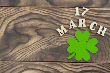 The inscription March 17 and a clover leaf on a dark wooden background. The concept of celebrating St. Patrick. Blank for congratulations on St. Patrick's Day. copy space. Flat layout. - 578604387