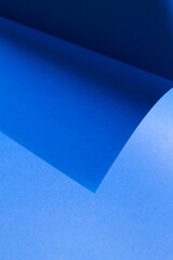 Monochrome composition formed by blue cardboard and the curvature it forms when folded.