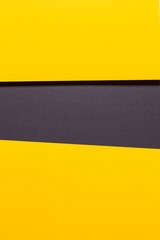 Geometric composition formed by two yellow cardboard, a black one and their shadows.