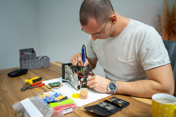The young master electronics engineer checks, repairs and finishes the motherboard he was given to...
