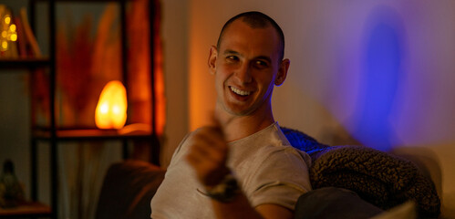 End of the working day of a young freelance programmer. He is sitting in the living room enjoying a cup of tea and checking social media on his laptop