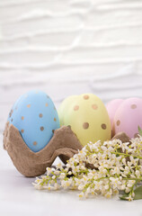 Colored eggs with white flowers on table. Easter. Copy space