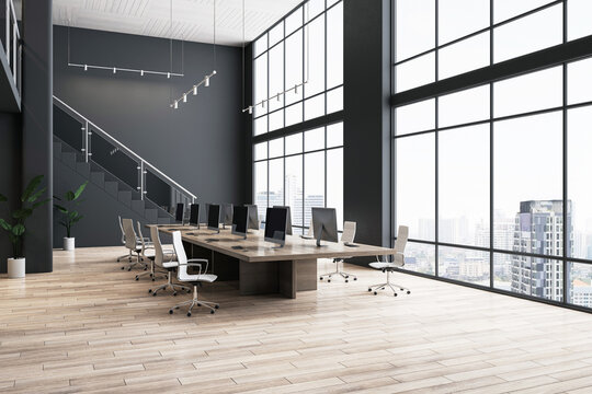 Perspective view on modern computers on wooden meeting table, light chairs around and city skyline view from panoramic window in spacious office with parquet floor and dark stairway. 3D rendering