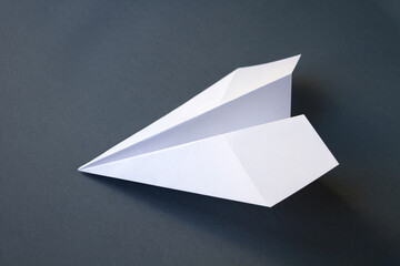 White paper plane origami isolated on a grey background