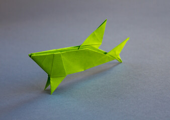 Green paper shark origami isolated on a grey background