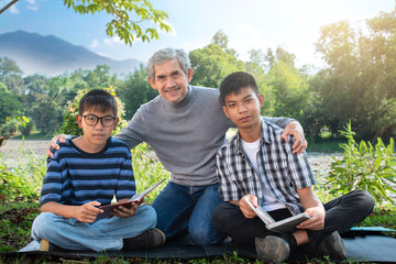 Grandfather and grandsons are spending summer times together at the park happily, soft and selective focus, concept for freetimes activity, hobbies, relaxing, family, summer and happiness of elders.