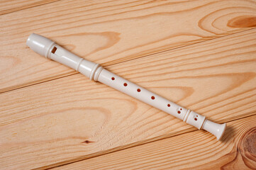 Block flute wind musical instrument photographed on a wooden surface.