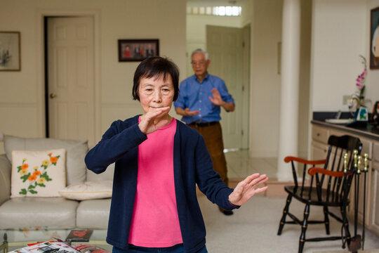 Asian Senior Woman and Man practicing Tai-Chi at home