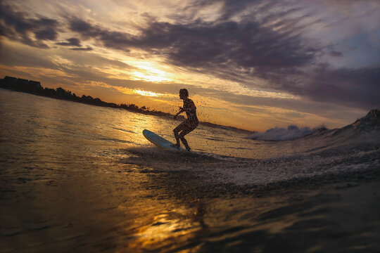 Young woman surfing at sunset