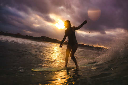 Young woman surfing at sunset