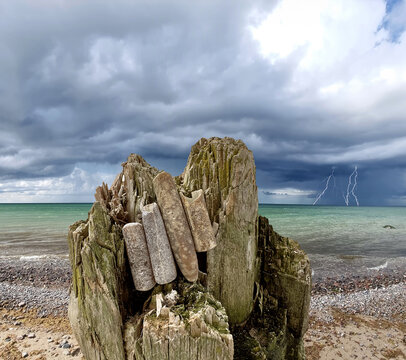 Donnerkeile in Reihe sortiert auf einem Baumstamm w&auml;hrend eines Gewitters am Ostseestrand