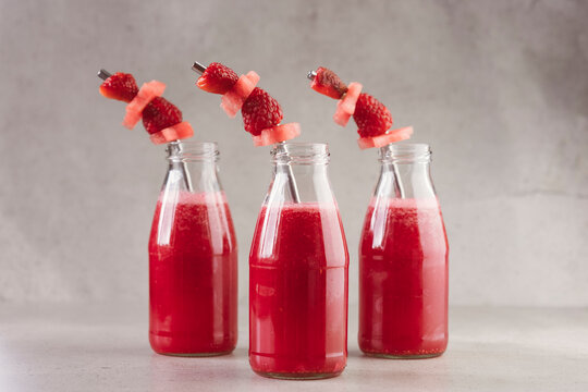 Side view of glass bottles of red berry fresh juice