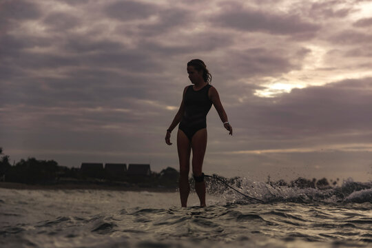 Young woman surfing at sunset
