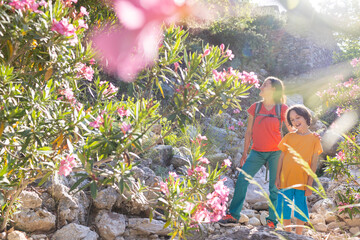 a boy with his mother walks in a beautiful park with oleander flowers