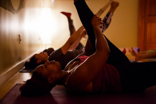 a small group of women practice stretches in a darkened room