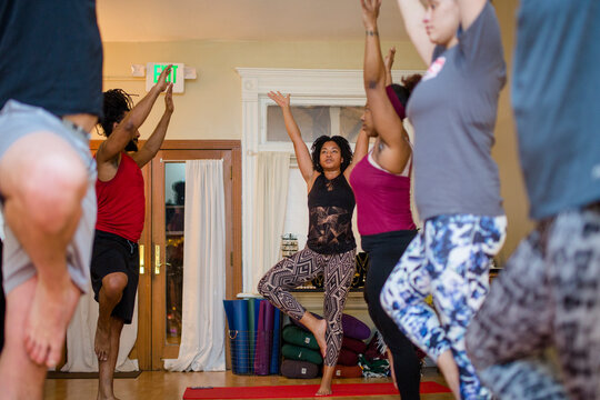 a class of yoga students raise their arms in a yoga pose