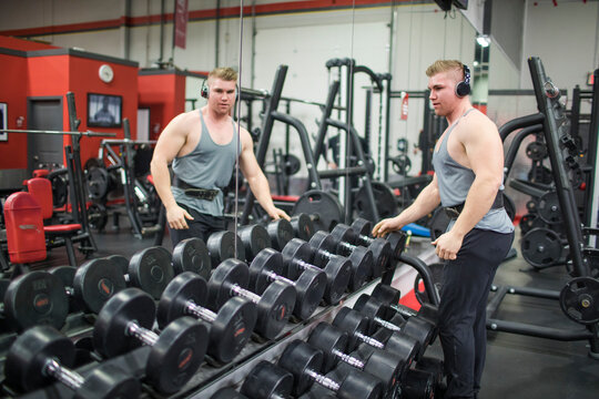 Bodybuilder selecting dumbbells of the rack at gym.