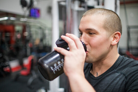 Fit man takes a drink of water during a workout.