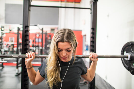Woman exercising in gym, using barbell